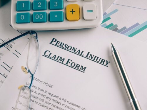 A personal injury claim form sits on a desk with glasses, a calculator, and a pen atop it. The paper includes instructions and partially visible charts, while reminders to avoid mistakes loom over the financial document in the background from the recent car accident.